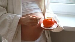 pregnant woman eats a persimmon Stock Footage
