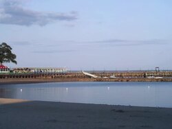 playland beach in Rye New York with people, fence, and trash cans at sunset with boardwalk and restaurant Stock Footage