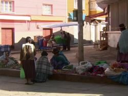 Traders selling fresh vegetables in small square, cart passes stacked with meat, Copacabana, Bolivia Stock Footage