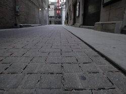 CU ground shot of permeable alleyway, street traffic in background Stock Footage