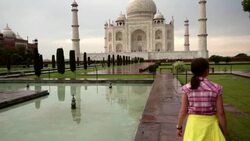 Steady cam shot of young girl walking toward Taj Mahal after rainstorm. Stock Footage
