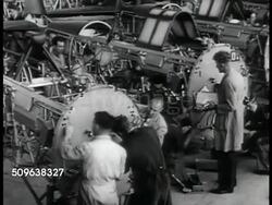 1941: AIRCRAFT: Sign: Commonwealth Aircraft Corp. WS INT Airplane factory floor. VS Men working on airplane bodies, engine. AMBULANCES: Rows of completed ambulances in yard. Male checking front of trucks in line. WS Ambulances in yard. WWII Instructional Video