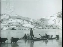Greenland expedition, 1934, by French explorers - CU explorers looking at camera, huskies pull boat over land Stock Footage
