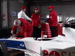 Wide shot mechanics working on Formula One race car / driver entering garage and greeting crew Stock Footage