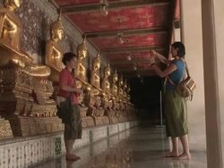 ZO ZI SHAKY Young woman photographing man in front of golden Buddha statue at Wat Phra Kaew (Temple of the Emerald Buddha), Bangkok, Thailand Stock Footage