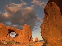 South Window Arch and North Window Arch at sunset with dramatic sky and clouds - pan Stock Footage