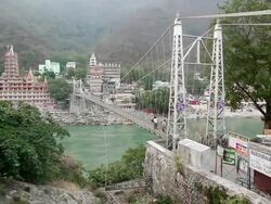 WS PAN View of Lakshman Jhula with holy city at waterfront / Rishikesh, Uttarakhand, India Stock Footage
