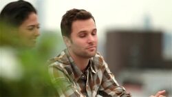 Hip young man on Brooklyn rooftop surprised by girlfriend with a kiss (dolly-shot) Stock Footage