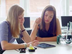 MS two female high school students working on project on digital tablet together in robotics class. Stock Footage