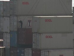 Dock worker stands on a shipping container as it is lowered onto dock by a crane, Hong Kong Stock Footage