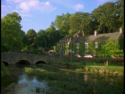 Rural Building, Swan Hotel, River Coln and Bridge, Bibury - ducks on river, trees on skyline Stock Footage