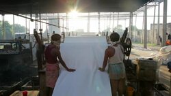 Laborers wash and roll recently dyed fabrics. Stock Footage