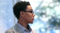 Hip young businessman leads meeting in office conference-room, points out numbers on white-board Stock Footage