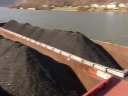 Medium Long Shot hand,held pan,right , Coal,filled barges are moored to a riverside dock at a coal distribution facility. / West Virginia Stock Footage