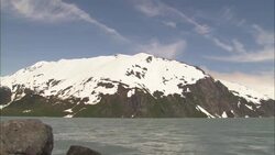 The Arctic Ocean flows near an ice-covered mountain in Alaska. Stock Footage