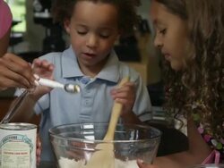 Slow motion pan of boy helping pour in baking powder. Stock Footage
