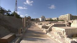 A modern communication tower contrasts with an ancient Roman amphitheater in Alexandria, Egypt. Stock Footage