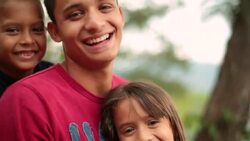 Hispanic teenage brother and younger siblings laugh at camera Stock Footage