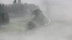 Looking down into the Langdale Valley above valley mist formed by a temperature inversion on Loughrigg, near Ambleside in the Lake District National Park, with cars driving on the Hawkshead road. Stock Footage