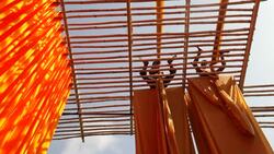 Two workers hang newly dyed fabrics over bamboo to dry. Stock Footage
