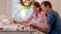 Man cuts pie dough into strips as woman bastes lattice-top pie and laughs (dolly-shot) Stock Footage
