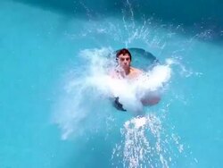 Slow motion medium shot man doing cannonball dive into swimming pool Stock Footage