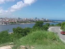 WS Car passing with Havana skyline in distance / Havana, Havana, Cuba Stock Footage