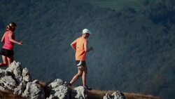 Two trail runners going down the grassy plateau Stock Footage