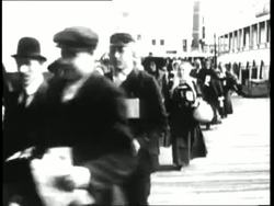 Immigrants carry their luggage on the dock of Ellis Island. News Clip
