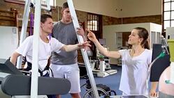 Physical therapists talking to man with spinal injury in hoist on treadmill Stock Footage
