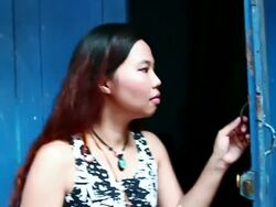 MS SLO MO Shot of Woman leaving building closing blue door behind her and putting note in her purse / Luang Prabang, Laos Stock Footage