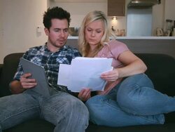 couple on sofa looking at bills Stock Footage