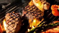 Steaks and vegetables sizzle on a grill. Stock Footage