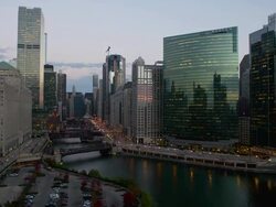 WS T/L View of skyscrapers with river and Wacker drive showing rail, boat, motor vehicle traffic as night falls / Chicago, Illinois, United States Stock Footage