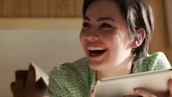 young woman looks up from tablet computer and laughs Stock Footage