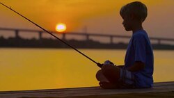 Boy fishing at dawn or dusk Stock Footage