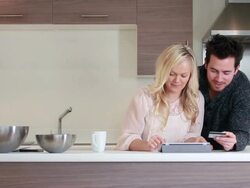 couple shopping online in kitchen Stock Footage