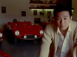 Young man in garage with vintage sports cars in background / smiling at camera Stock Footage