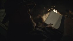 Middle-Aged Caucasian Male Reads by Campfire Stock Footage