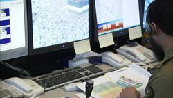 A security officer processes paperwork near security monitors. Stock Footage