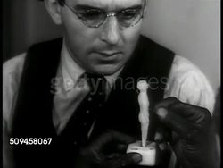 1937: VOODOO ARTICLE: Writer Joseph Mitchell sitting at desk watching unidentified person sticking pin in wax doll figure. MS Paper in typewriter w/ beginning of VOODOO article. CU Front page of  World-Telegraph newspaper, 'Voodoo Harlem' headline. Instructional Video
