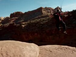 WS PAN TD SLO MO Man flying off cliff and parachuting to ground / Moab, Utah, United States   Stock Footage