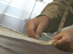 CU TD Shot of man with measuring tape around his neck pinning sewing pattern onto fabric / South Africa Stock Footage