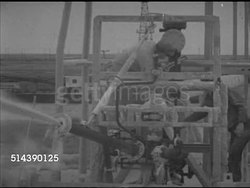 1952: GULF COAST PIPELINE: PAN Rural land w/ distant buildings, MINING: VS Sulfur spraying from pipe, workers tending machine. VS Crane bucket scooping into solidified sulfur block, turning to empty, scooping again. Note: Poor contrast, sulphur. Instructional Video