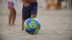 Cute Brazilian boy dribbles soccer ball in the sand on Copacabana Beach Stock Footage