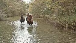 SLO MO DS Three people riding horses across river Stock Footage