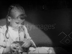 1952: MOROCCAN ARTS & CRAFTS: VS Women  & children weaving carpet by hand, weaver pushing strand down tight, child unwrapping yarn off fingers, young woman working side by side on loom, woman separating strands, pushing, pulling material.  Textiles. Instructional Video
