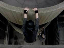 Low angle medium shot freerunner looking down over ledge / high angle tilt down two freerunners hanging from ledges and climbing up Stock Footage