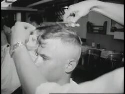 A new military cadet gets a close haircut. News Clip