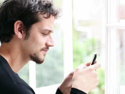 Young man sending an SMS on his mobile phone Stock Footage